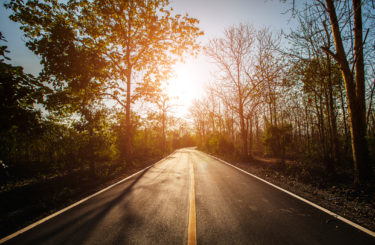 Empty asphalt road through the green field and clouds on blue sky in summer day.