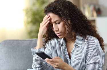 Worried latin woman reading on phone bad news