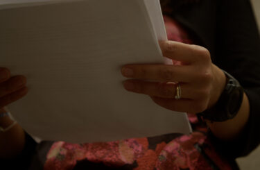 Woman holds pages, ready to write business story.