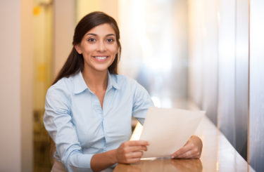 Smiling Pretty Woman Holding Document in Cafe