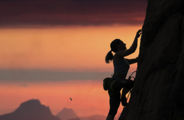 Silhouette of female alpine climber against sunset