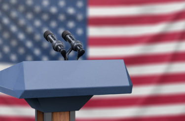 Flag of the United States at a press conference with microphones