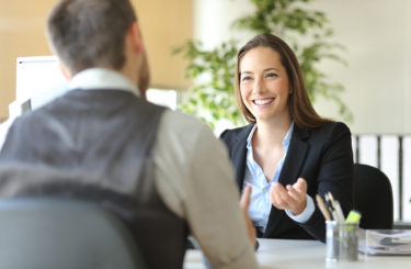 Happy executive coworkers laughing and talking at the office