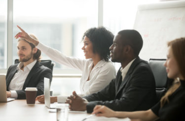 African woman raising hand to ask question at team training