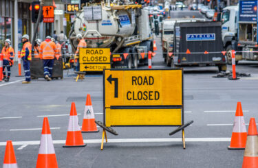 Melbourne, Victoria, Australia, July 31st, 2022: Workers are wearing high visibility clothing while performing roadworks behind a 'Road Closed' sign