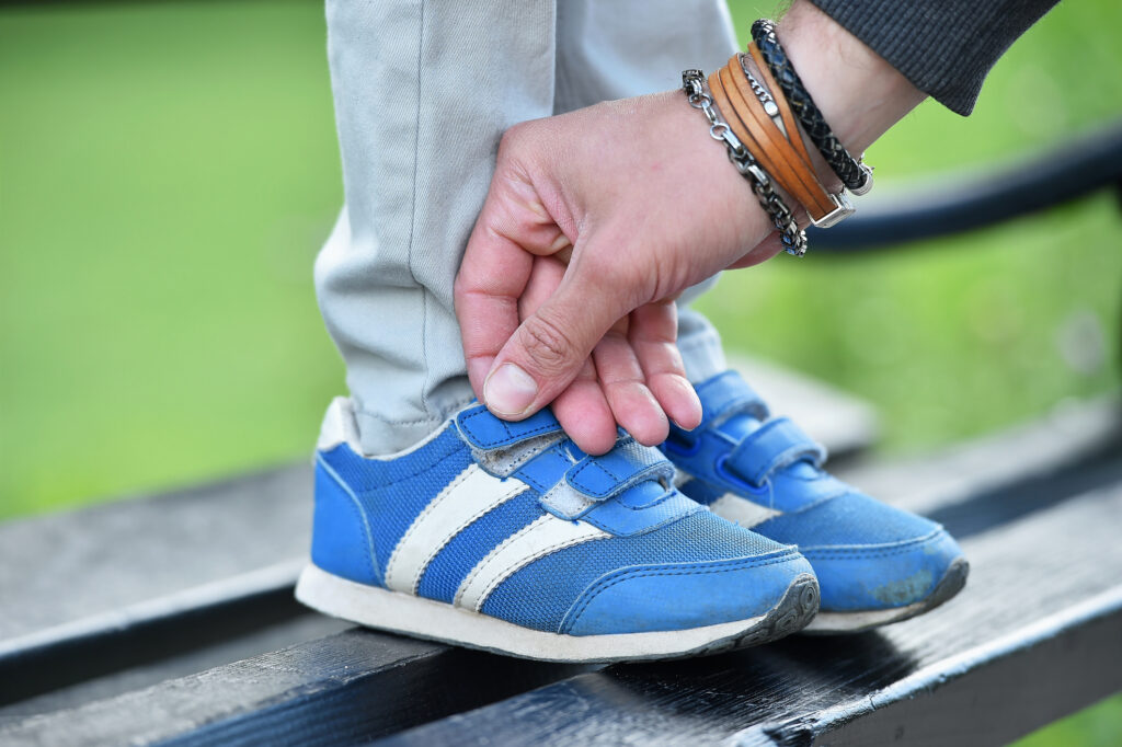 man tying velcro snickers on child
