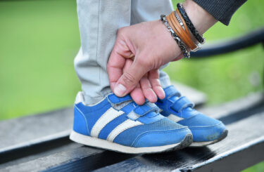 man tying velcro snickers on child