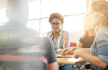 Candid picture of a business team collaborating. Filtered serie with light flares, bokeh  and warm sunny tones.